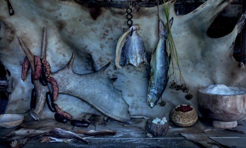 A spread of Arctic provisions including, from left, sun-dried white trout, moose antler, venison sausage, caribou blood sausage, dried Arctic flounder, dried sea bream, caribou lichen, meadow onion stems and seed heads, dried wild crowberries and geothermal Arctic sea salt against a deer hide backdrop.