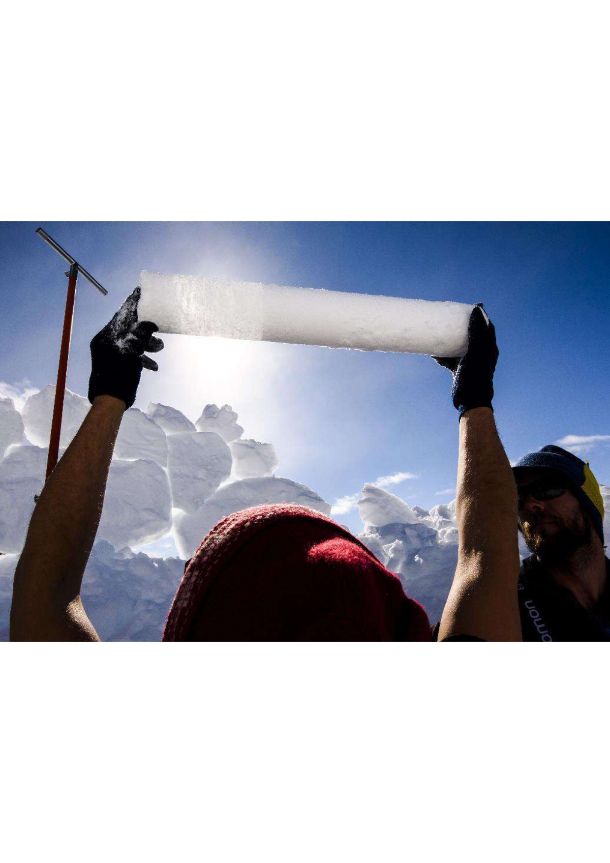 Alun Hubbard holds up a section of the ice core. The visible divide between superimposed ice on the left and snow firn on the right reveals hot summer melt and refreezing events.