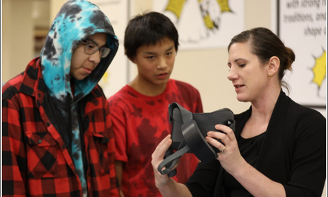 Lindsey Boechler showing two youths how to use a VR headset.